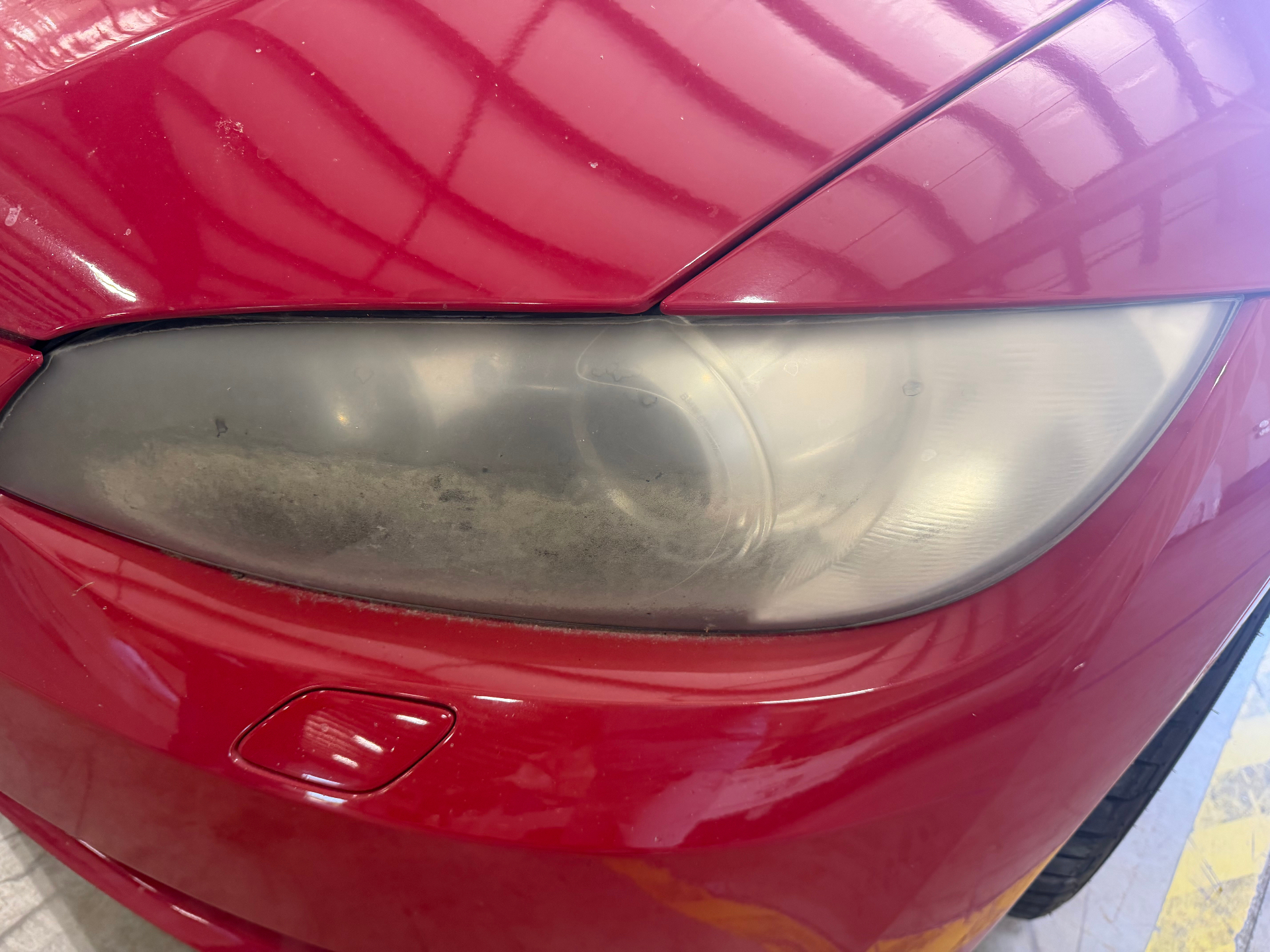 BMW headlight before restoration showing heavy oxidation and yellowing